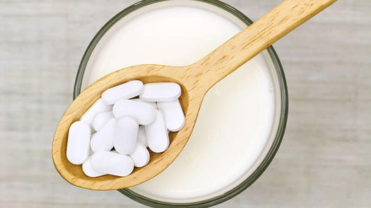 A wooden spoon holding white tablets above a glass of liquid, related to Miracle Mineral Solution.