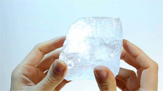 Hands holding a clear mineral block, illustrating the concept of Minerals in various forms.