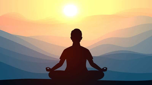 Meditation Gives Brain a Charge - silhouette of person meditating at sunrise with mountains in background.