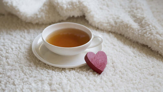 Tea to Detoxify and Calm Digestion served in a white cup with a heart decoration on a soft blanket.