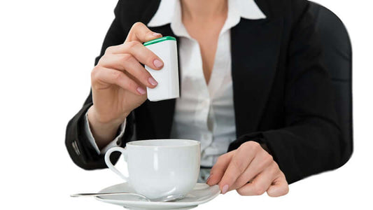 Woman in a business suit adding a sweetener to her coffee, relating to Aspartame FDA Approved Deadly Neurotoxin.