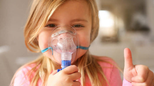 Child using nebulizer for magnesium nebulizing treatment and giving a thumbs up.