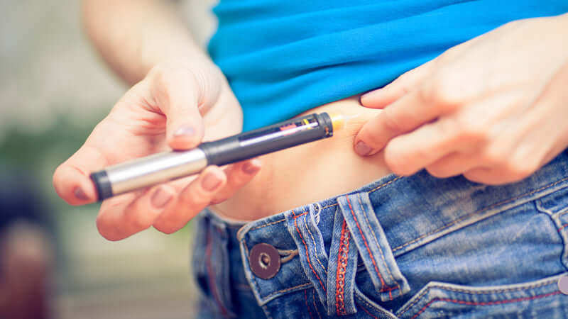 Person injecting insulin using a pen, related to the book Insulin: Our Silent Killer. Book Insulin featured.