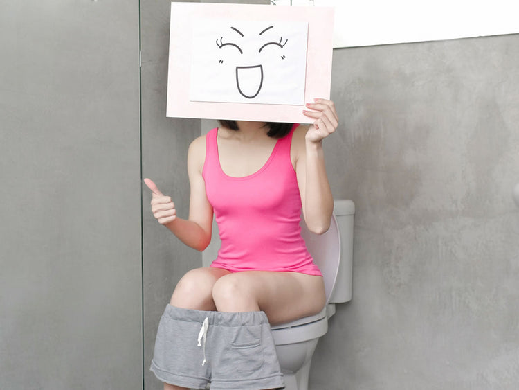 Woman sitting on a toilet, holding a sign with a happy face, thumbs up, promoting comfort and positive digestion.