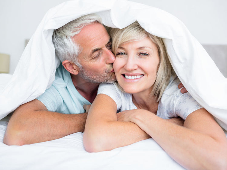 Couple under white blanket enjoying intimacy, representing Adult Stamina Supplements for enhanced sexual vitality.