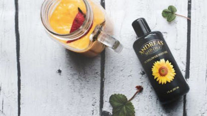 Cold Pressed Sunflower Oil bottle next to a smoothie in a mason jar on a wooden surface.