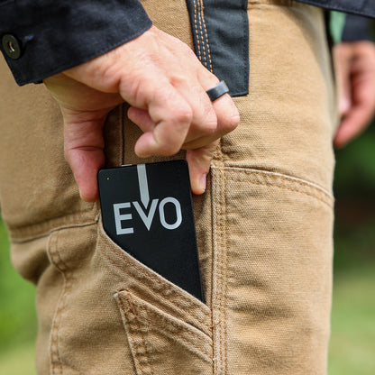 A close-up of a person's hand reaching into a tan canvas utility pocket to pull out a black card or case with the white text 'EVO' printed on it.