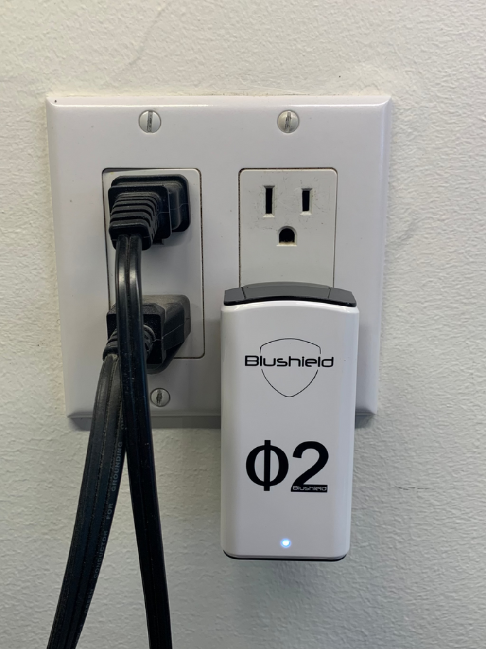 Phi 2 Plugin for EMF Protection for Small Homes, plugged into an electrical outlet with cords.