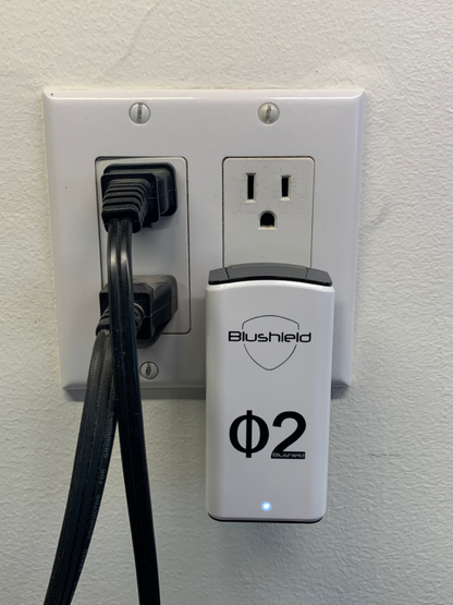 Phi 2 Plugin for EMF Protection for Small Homes, plugged into an electrical outlet with cords.